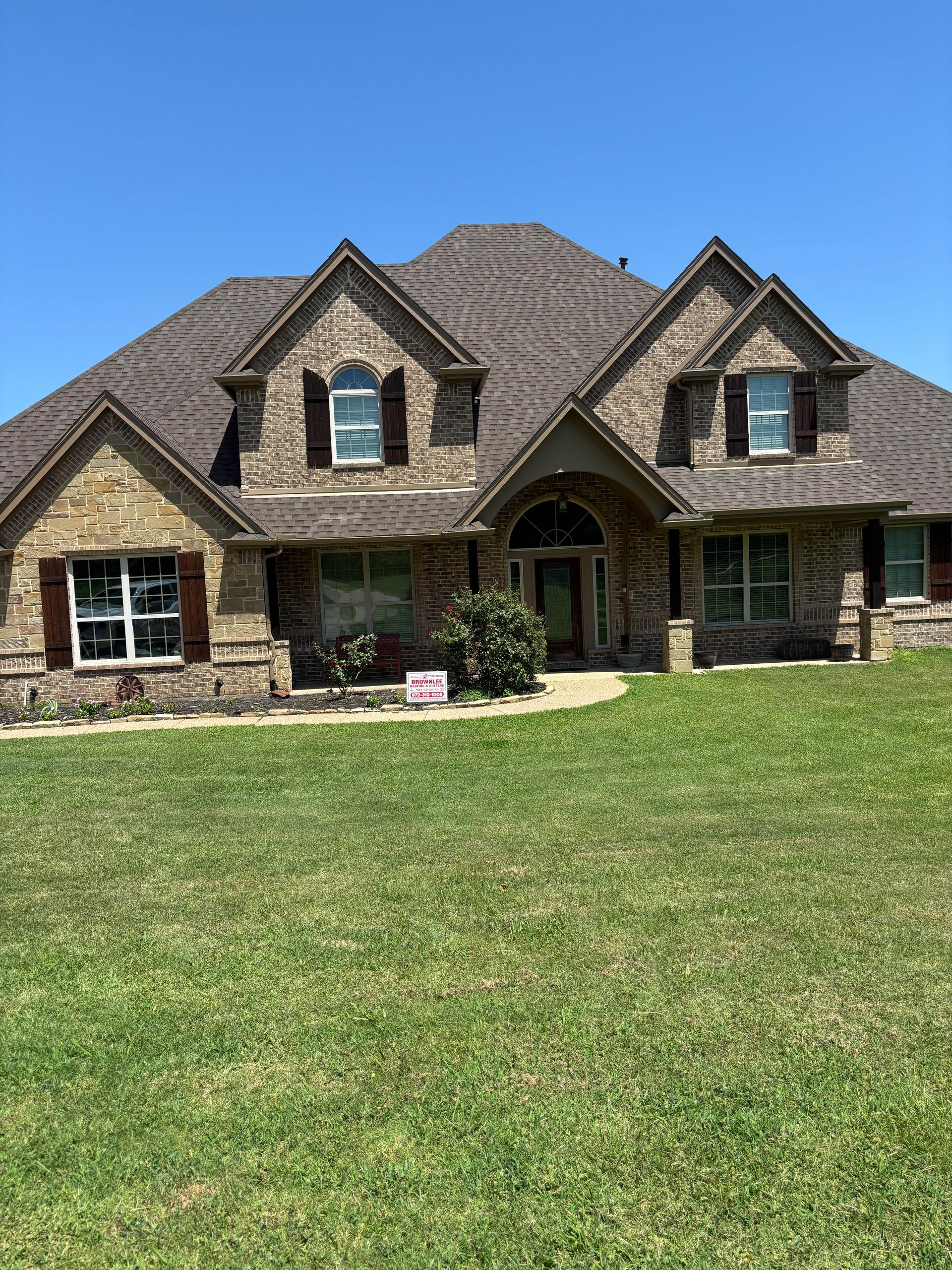A large brick house with a lush green lawn in front of it.
