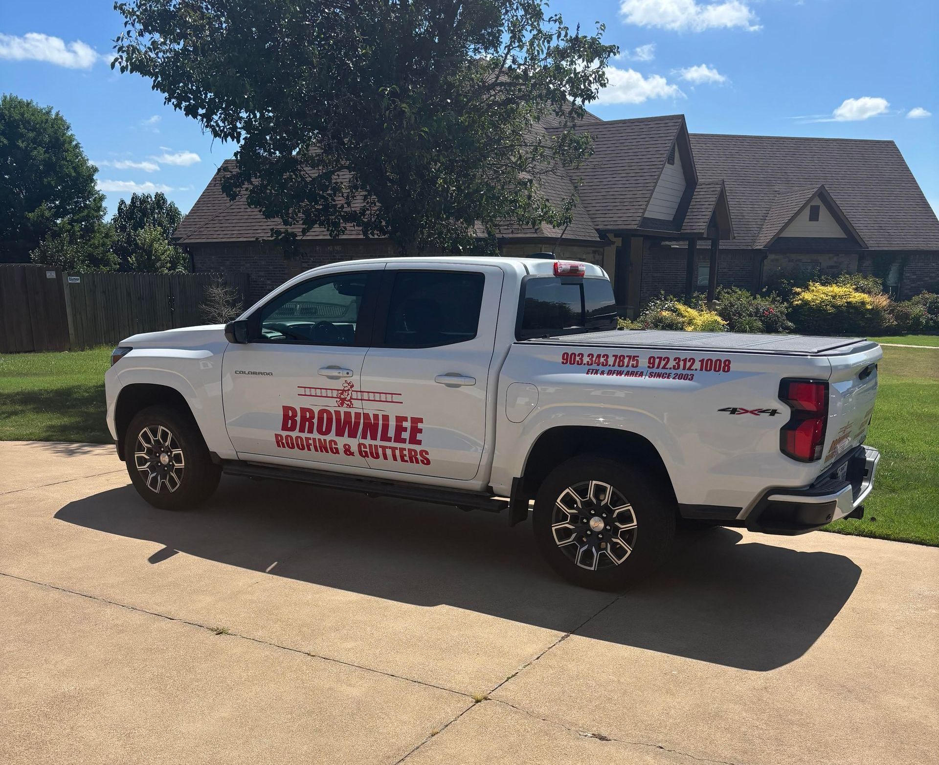 A white brownlee truck is parked in front of a house