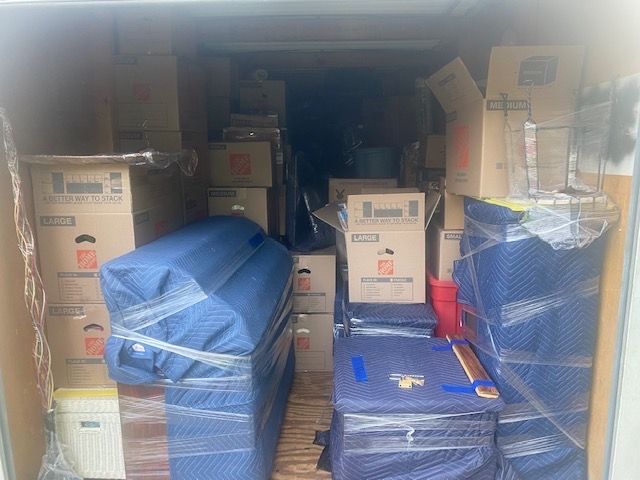 Interior of a moving truck packed with boxes and furniture wrapped in blue padding.