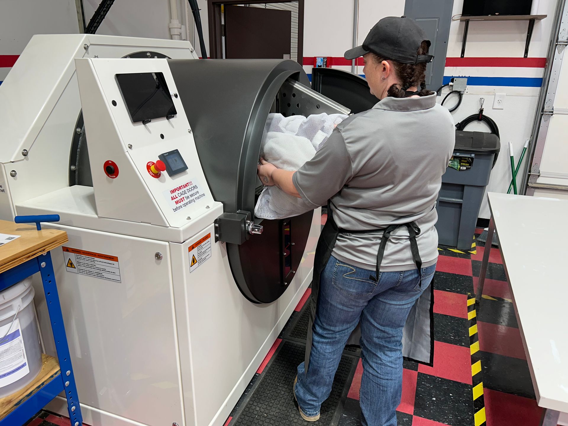 Person loading laundry into a large industrial washing machine.