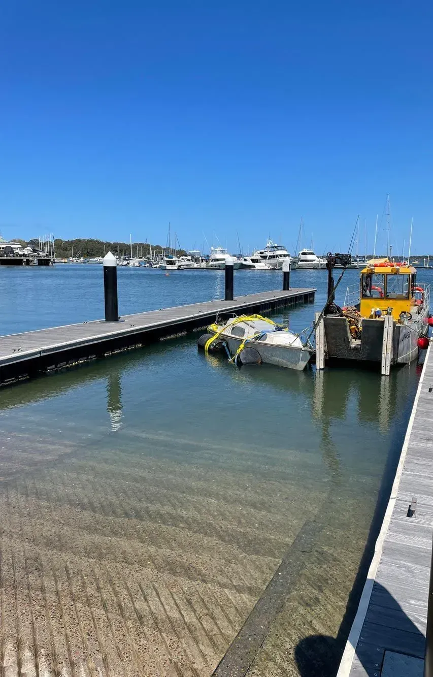 A Boat Ramp Entering a Calm Bay with A Yellow Work Boat — M&J Marine Services in Coffs Harbour, NSW