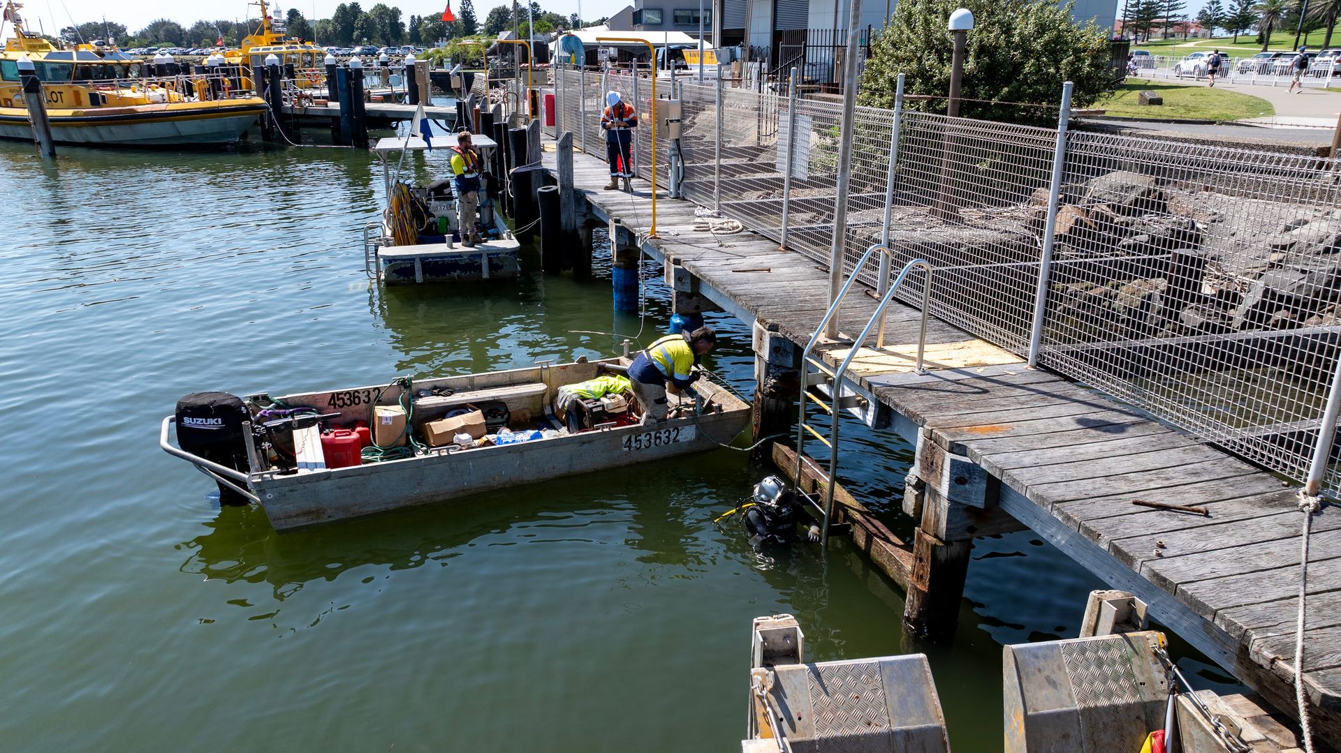 Workers Unload Gear from A Small Aluminum Boat at A Waterfront Pier — M&J Marine Services in Coffs Harbour, NSW