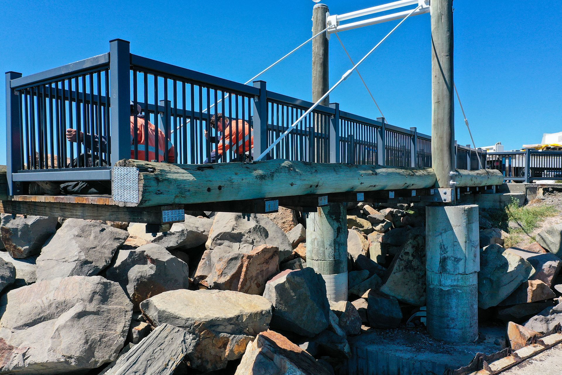 Workers in Orange High-Visibility Gear Stand on A Wooden Footbridge — M&J Marine Services in Lake Macquarie, NSW