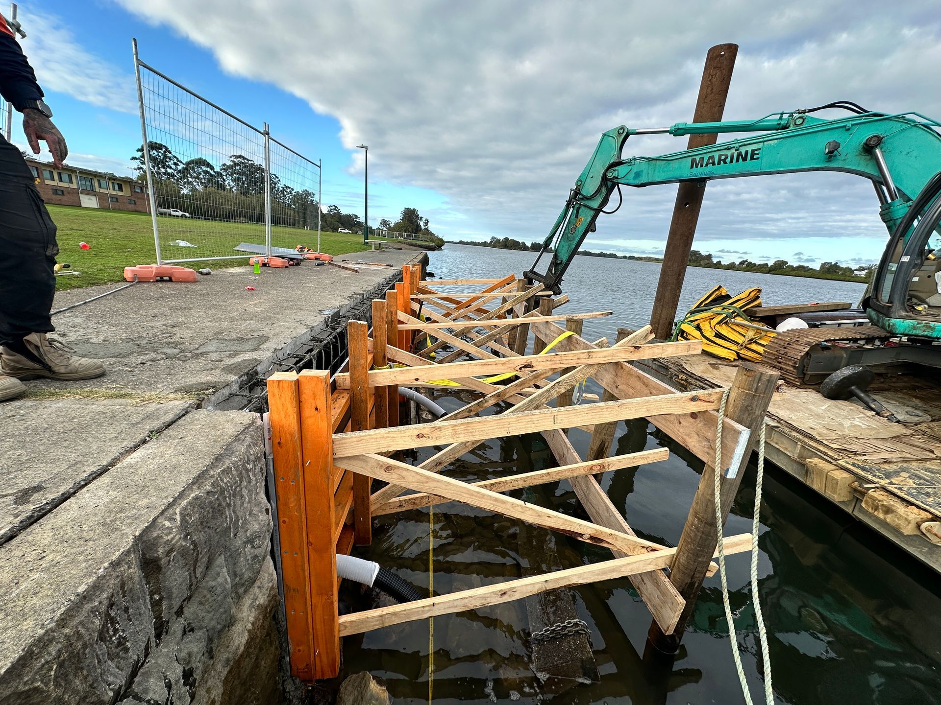 A Turquoise Excavator Works on A Wooden Framework — M&J Marine Services in Newcastle, NSW