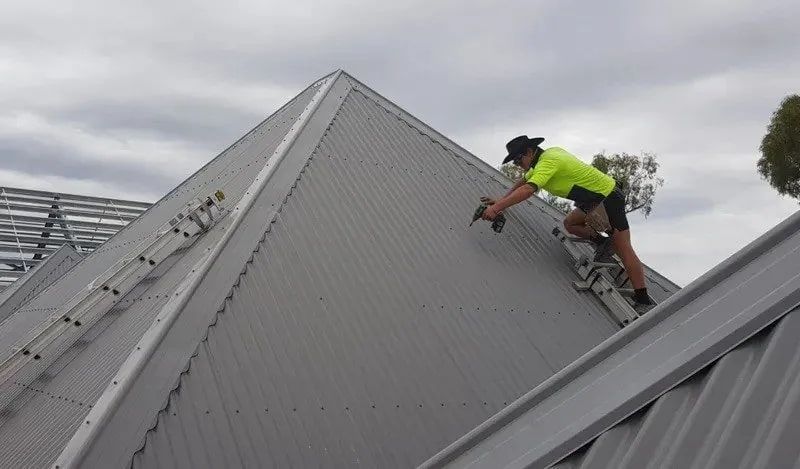 Two Men Are Working On The Roof Of A Building — Kosick Roofing NQ Pty Ltd In Mount Low, QLD