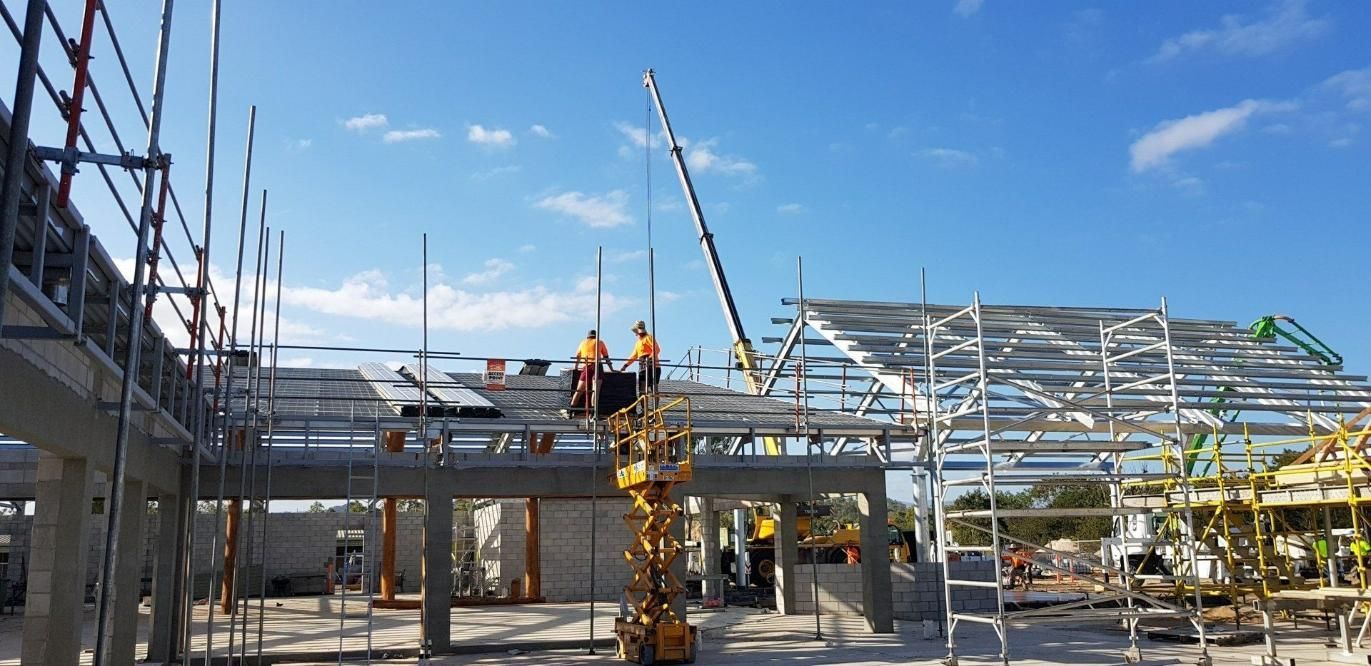 A Group Of Construction Workers Are Working On A Building Under Construction — Kosick Roofing NQ Pty Ltd In Mount Low, QLD