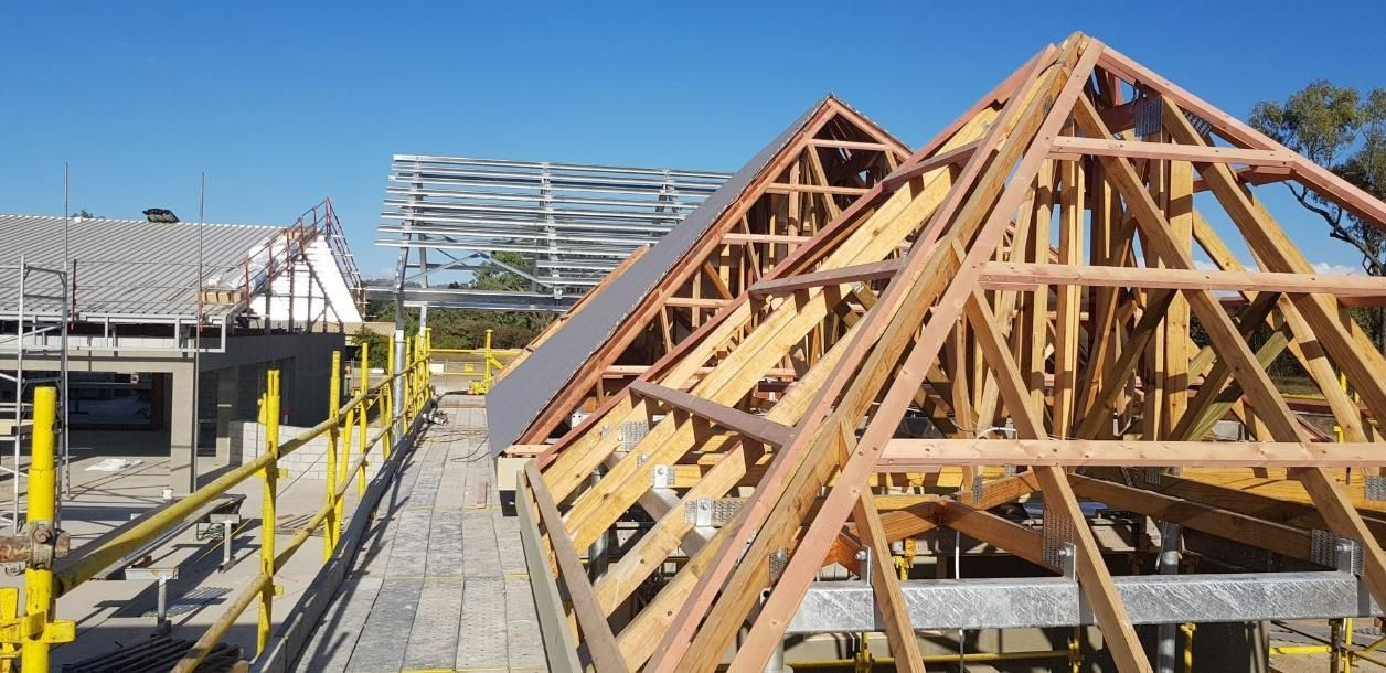 The Roof Of A Building Is Being Built With Wooden Beams — Kosick Roofing NQ Pty Ltd In Mount Low, QLD