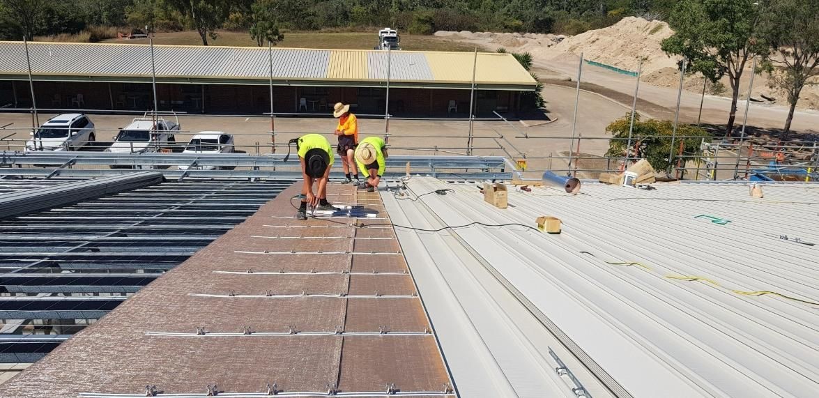 A Group Of Construction Workers Are Working On The Roof Of A Building — Kosick Roofing NQ Pty Ltd In Mount Low, QLD