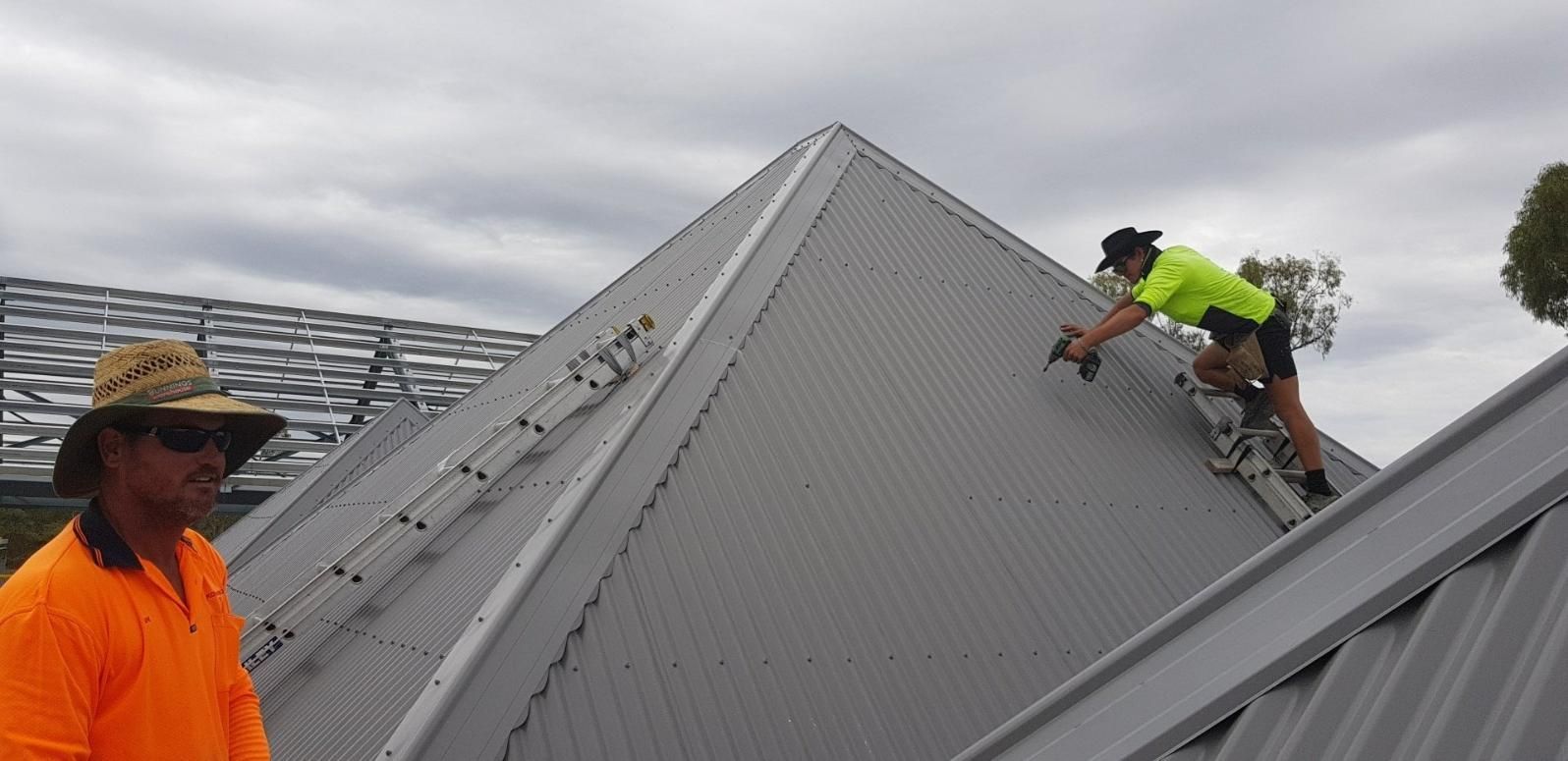 Two Men Are Working On The Roof Of A Building — Kosick Roofing NQ Pty Ltd In Mount Low, QLD