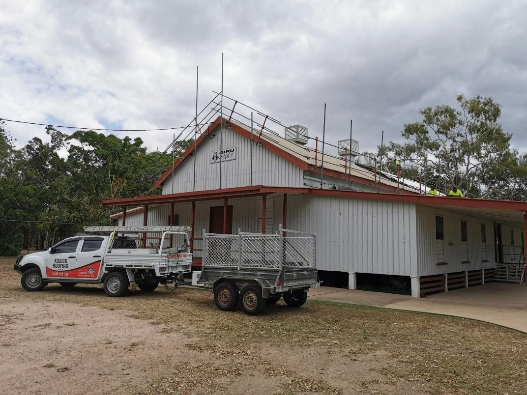 Two Trucks Are Parked In Front Of A Building With A Trailer Attached To It — Kosick Roofing NQ Pty Ltd In Mount Low, QLD