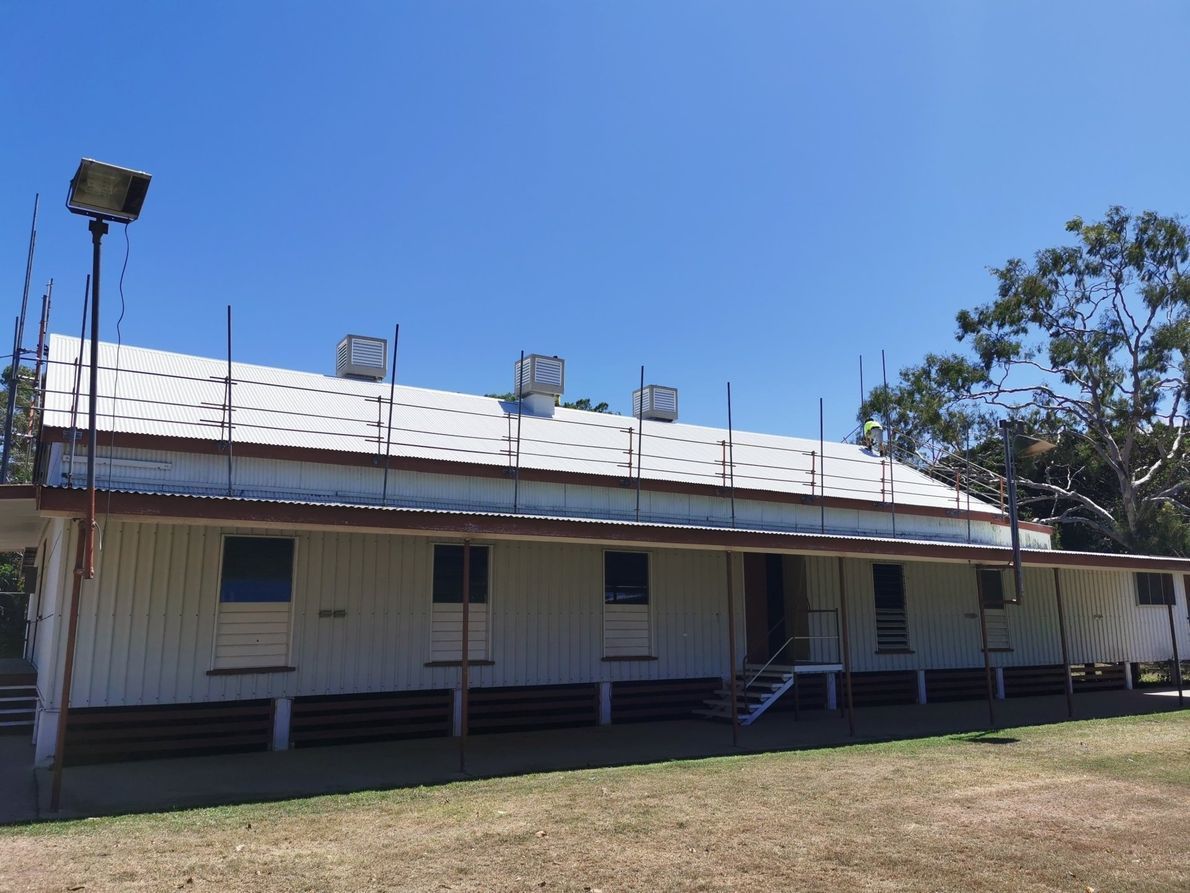 A Large White Building With A Roof That Is Covered In Shingles — Kosick Roofing NQ Pty Ltd In Mount Low, QLD