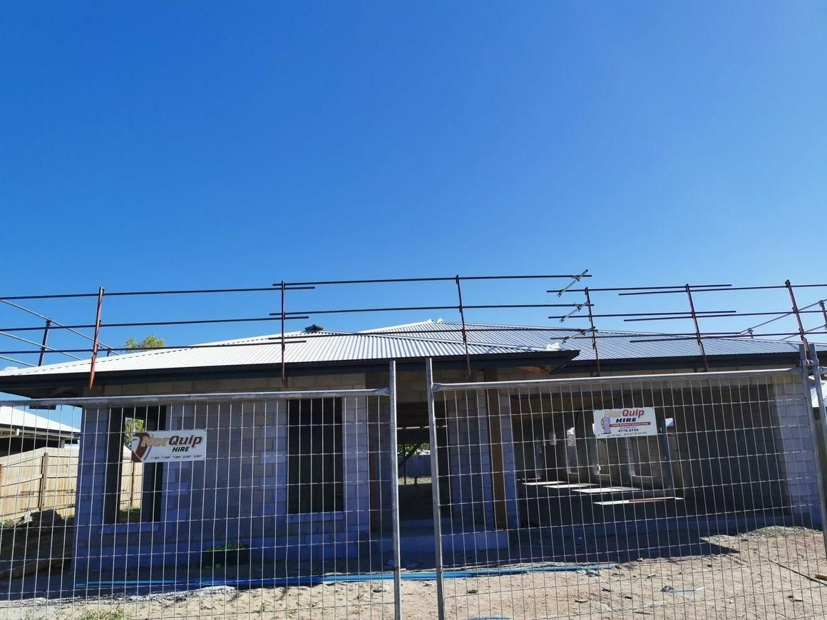 A Building Under Construction With A Fence Around It And A Blue Sky In The Background — Kosick Roofing NQ Pty Ltd In Mount Low, QLD