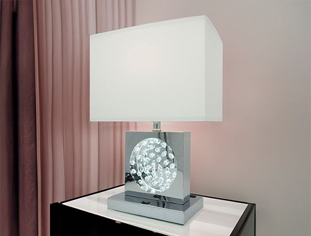 A lamp with a white shade is sitting on a table