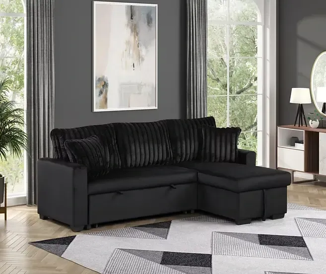 A black sectional couch is sitting in a living room next to a window.