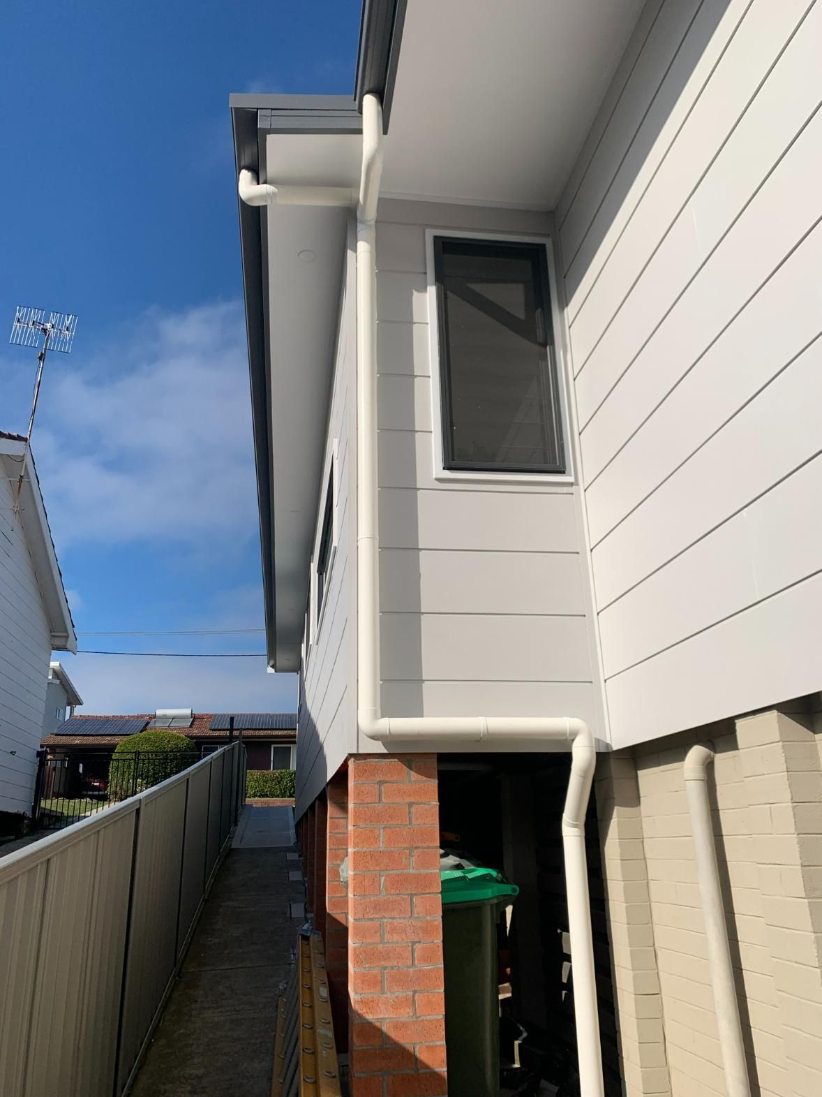 A White House With A Green Trash Can Under It — Oceanforce Plumbing In Blacksmiths, NSW