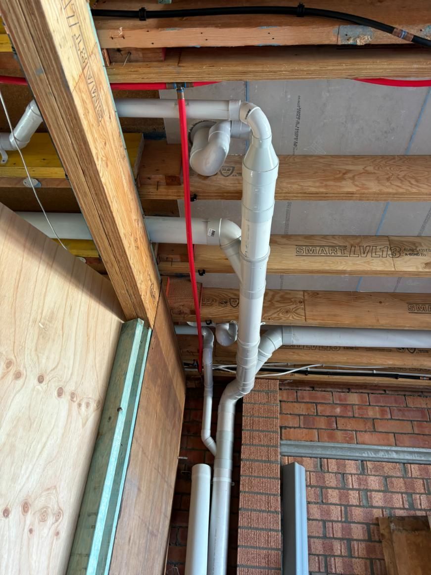 A Bunch Of Pipes Are Hanging From The Ceiling Of A Building — Oceanforce Plumbing In Wallsend, NSW