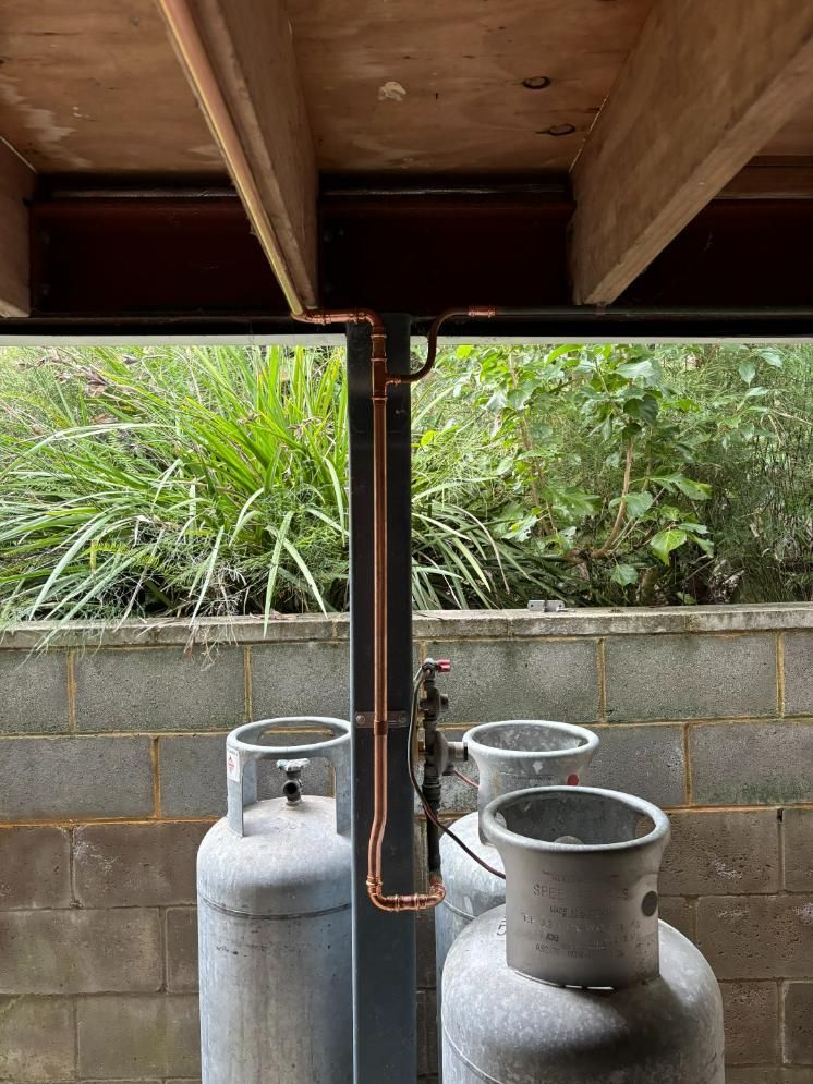 Three Gas Cylinders Are Sitting Under A Wooden Beam — Oceanforce Plumbing In Blacksmiths, NSW