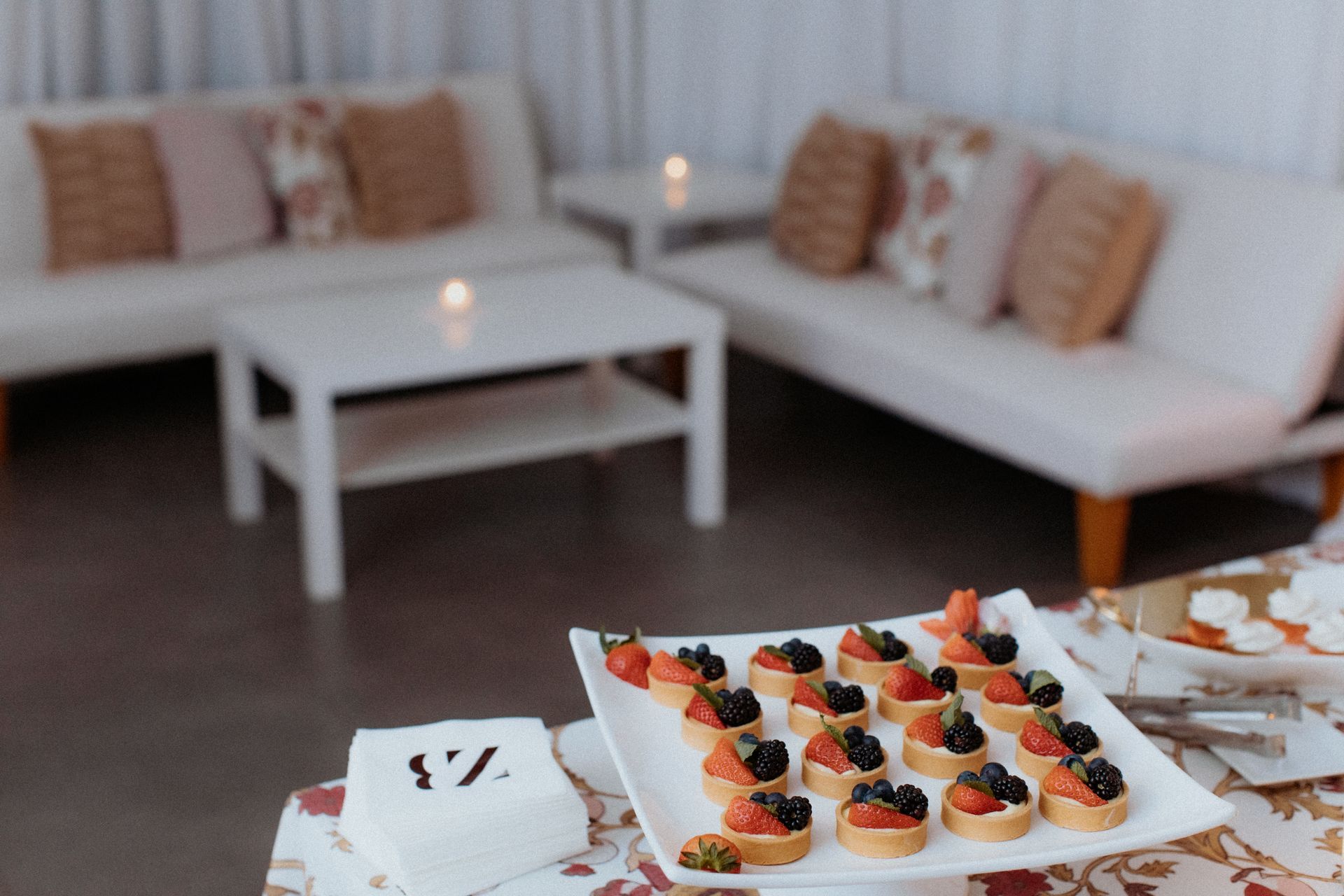 A plate of desserts with berries on a table in a living room.