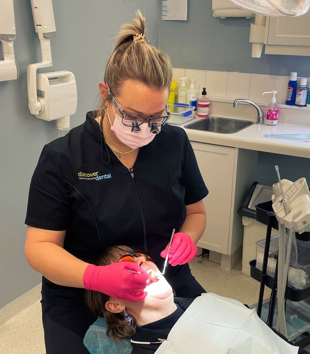 A female hygienist is examining a women's teeth in a dental office.