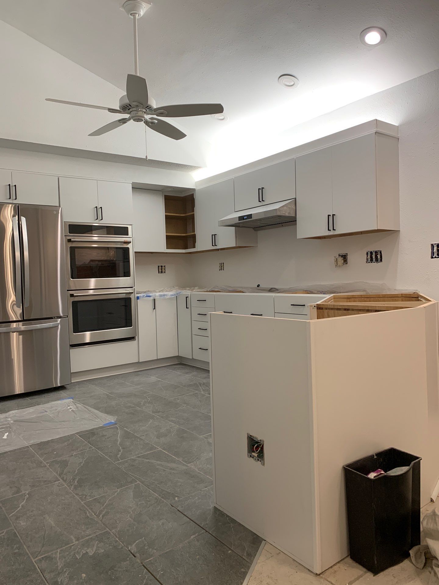 A kitchen with white cabinets and stainless steel appliances and a ceiling fan.
