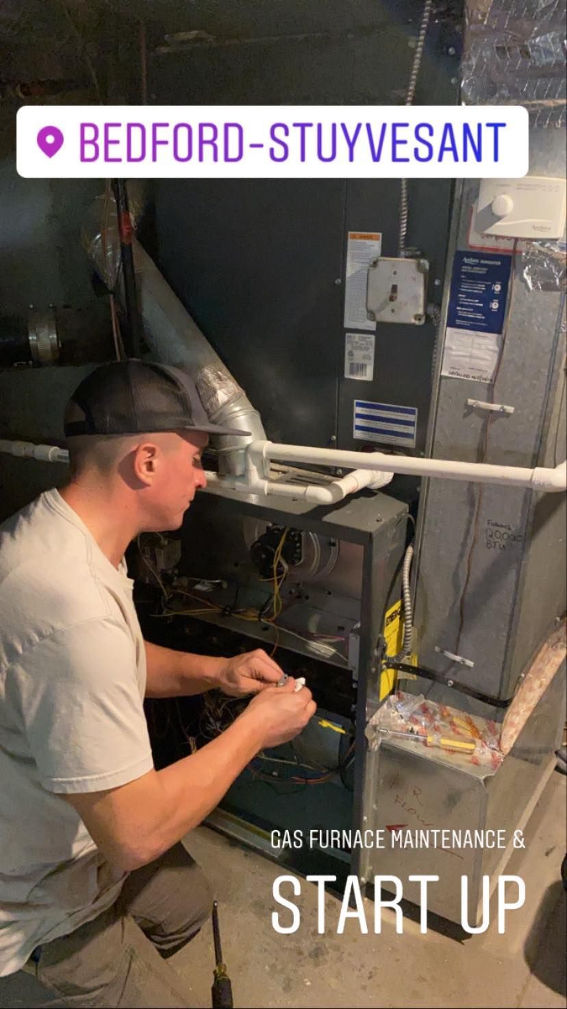A man is working on an air conditioner in a basement.