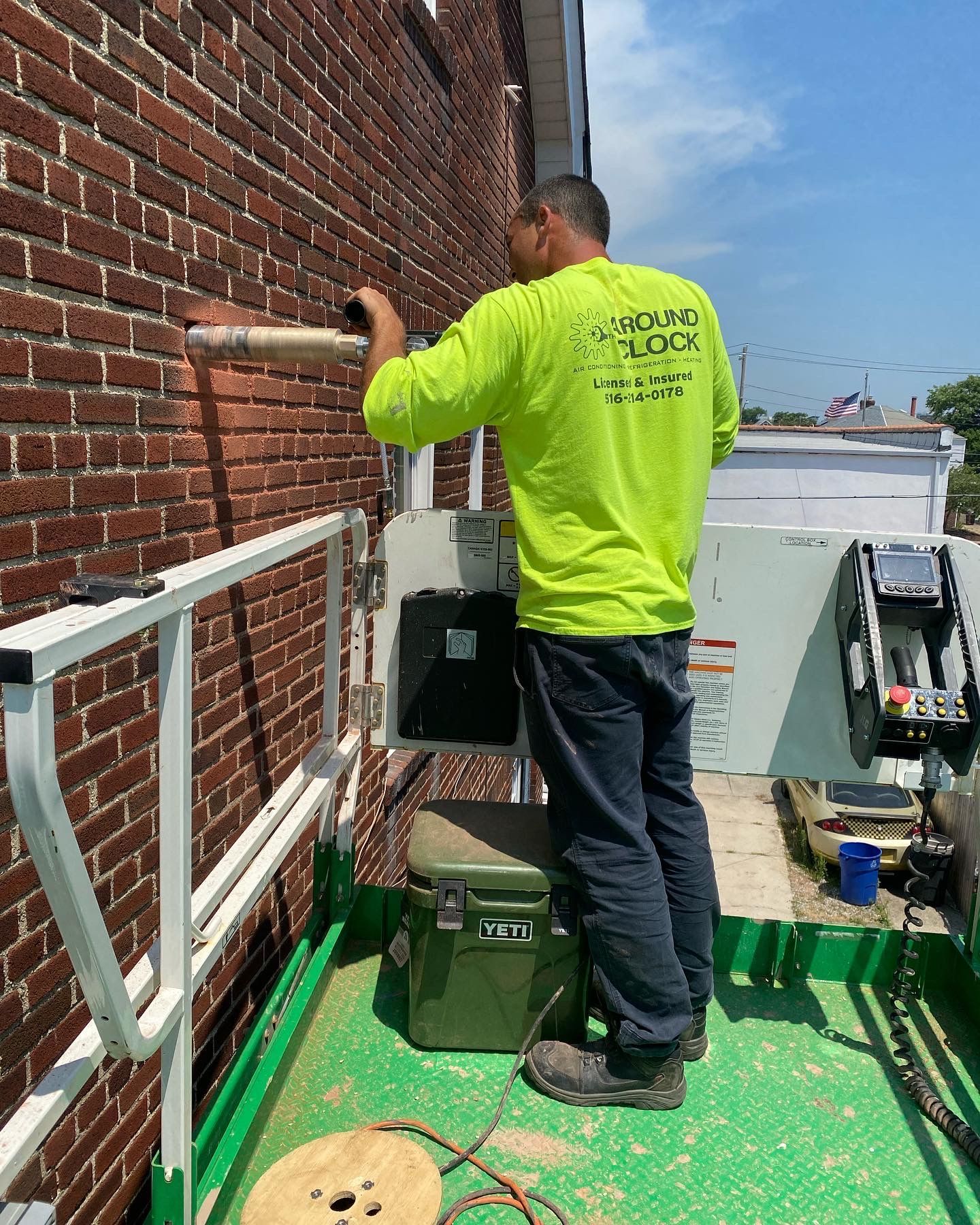 A man in a neon green shirt is working on a brick wall.