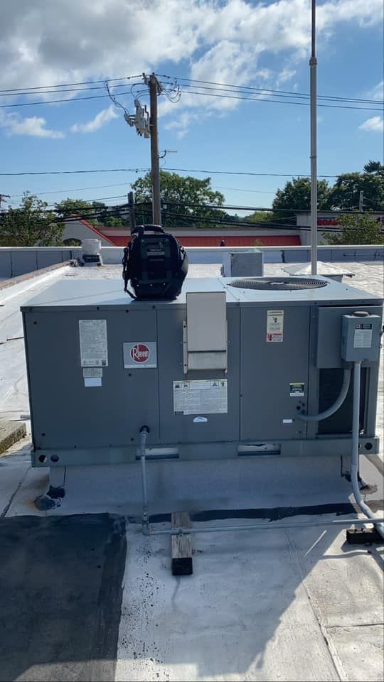 A backpack is sitting on top of a rooftop air conditioner.