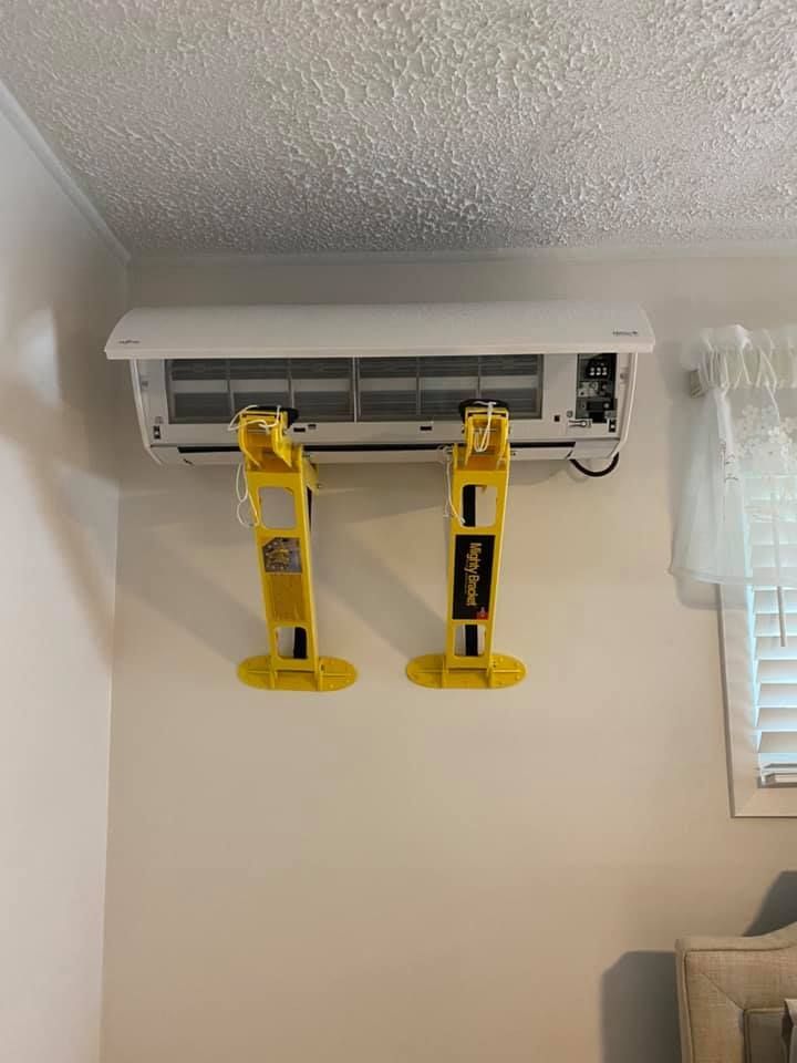 A wall mounted air conditioner with two yellow brackets attached to it.