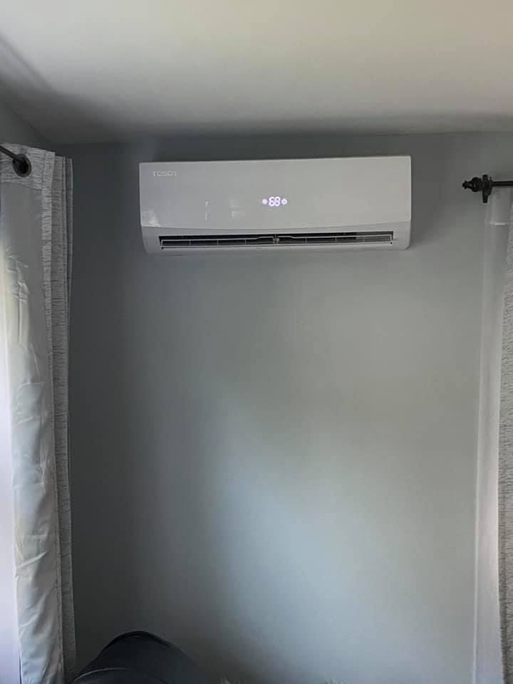 A room with a window and a wall mounted air conditioner.