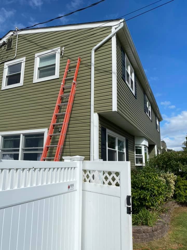 A ladder is sitting on the side of a house next to a white fence.