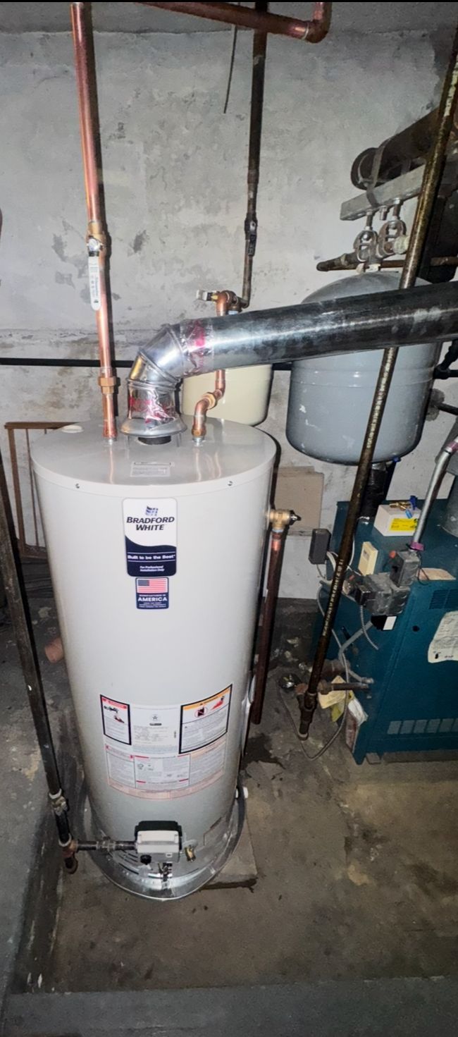 A white water heater with copper pipes in a basement setting.