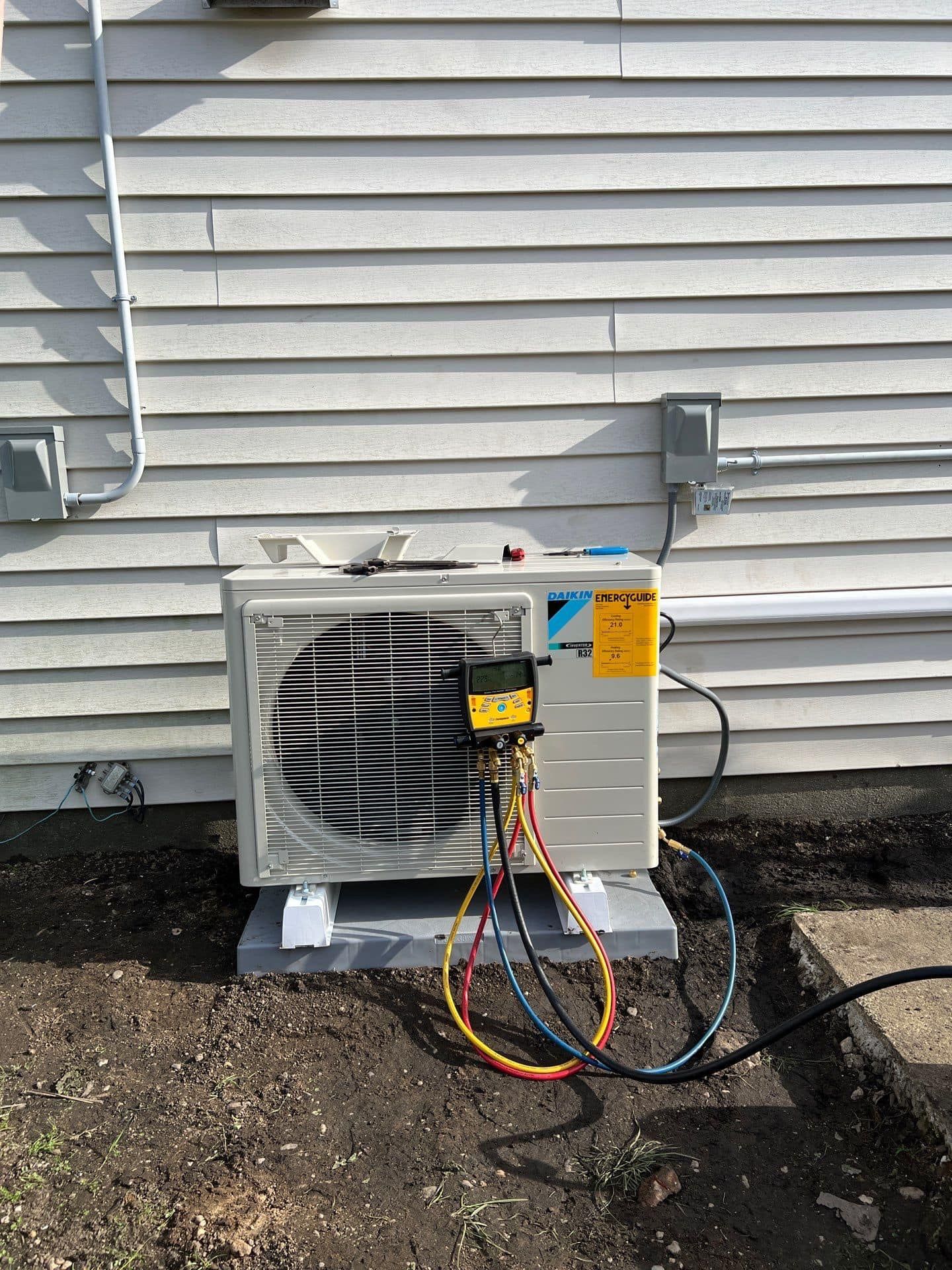 An air conditioner is being installed on the side of a house.
