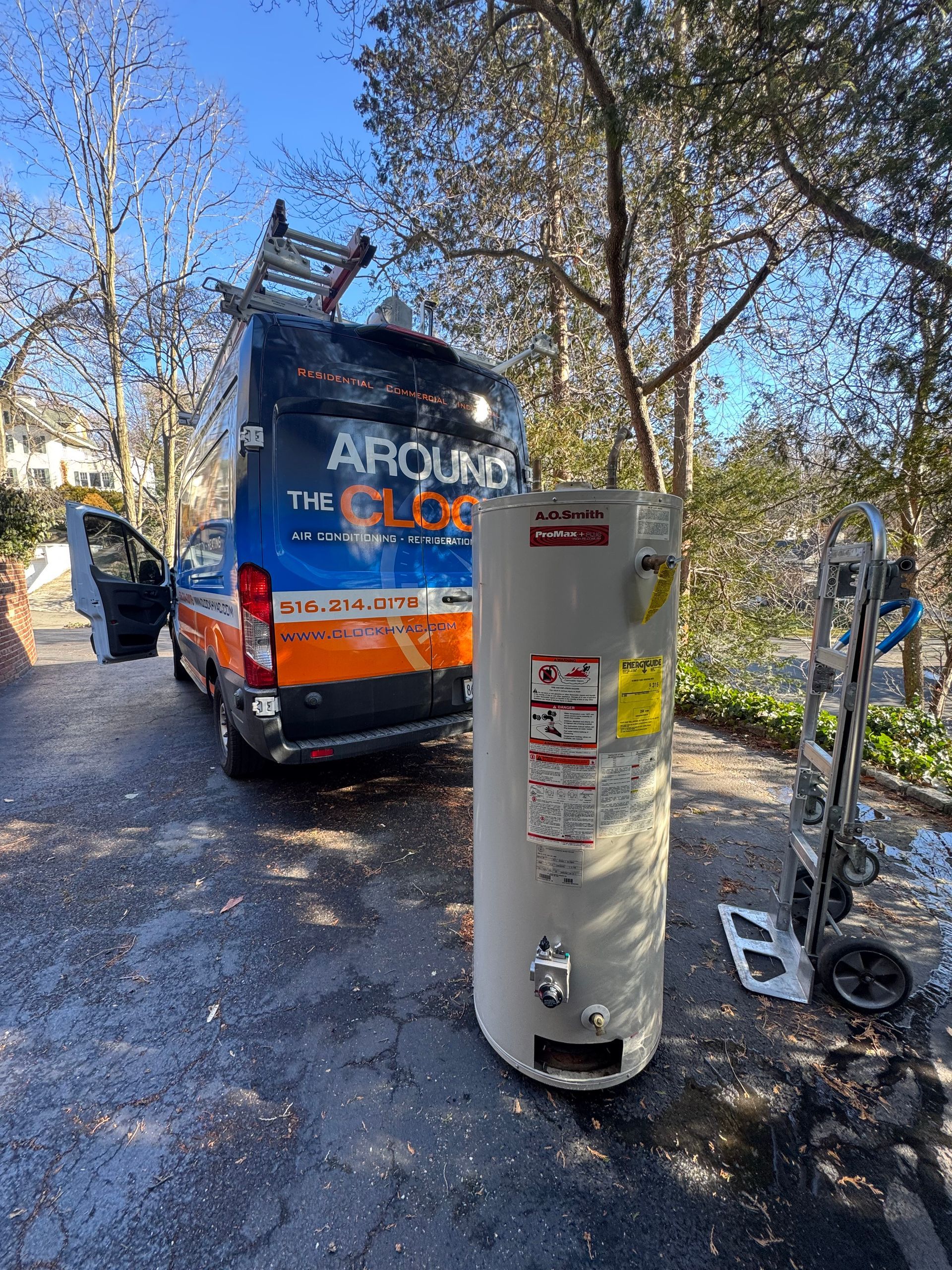 Water heater next to a service van with a ladder. The van has text reading 