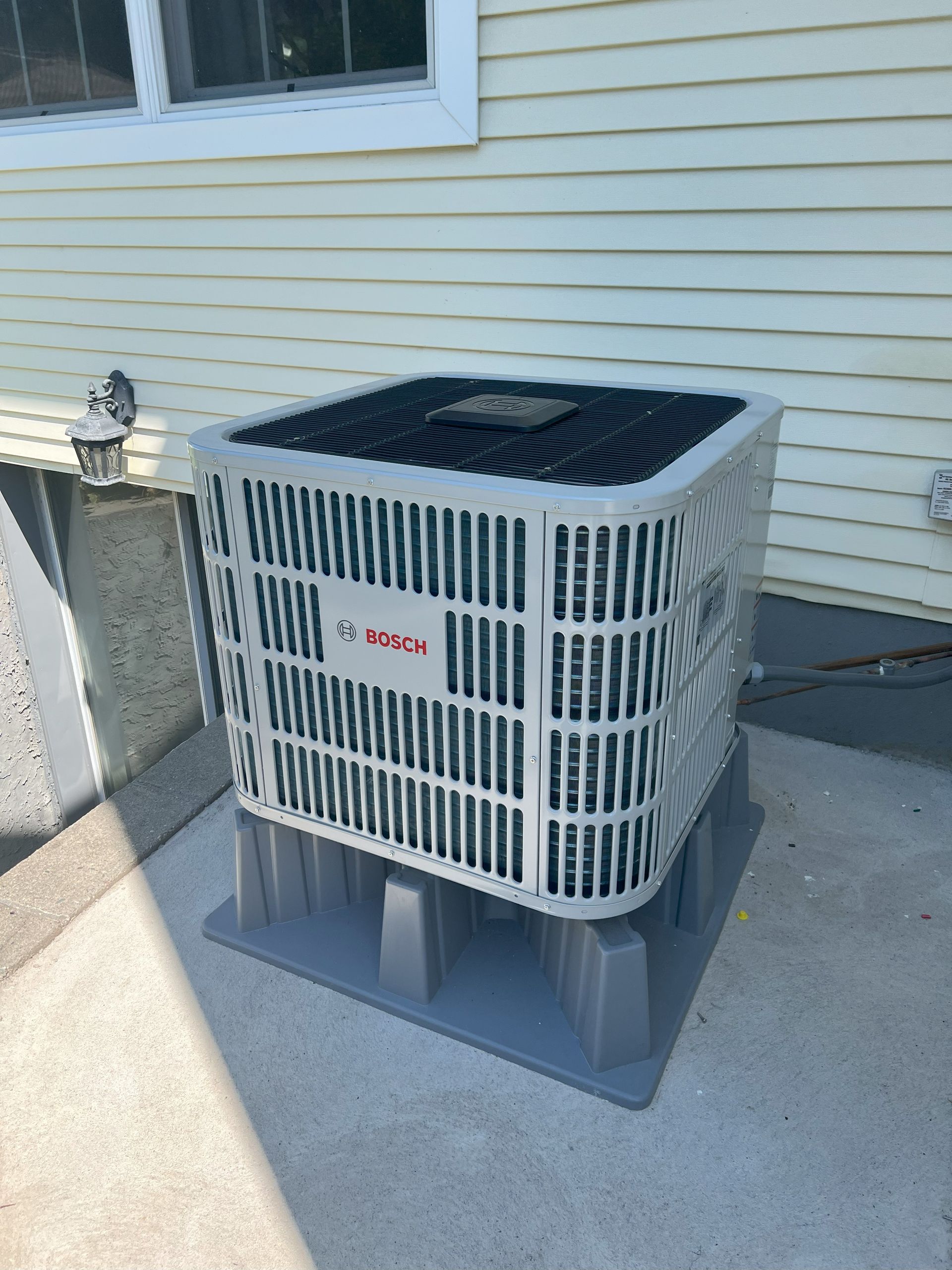 A white air conditioner is sitting on the side of a house.