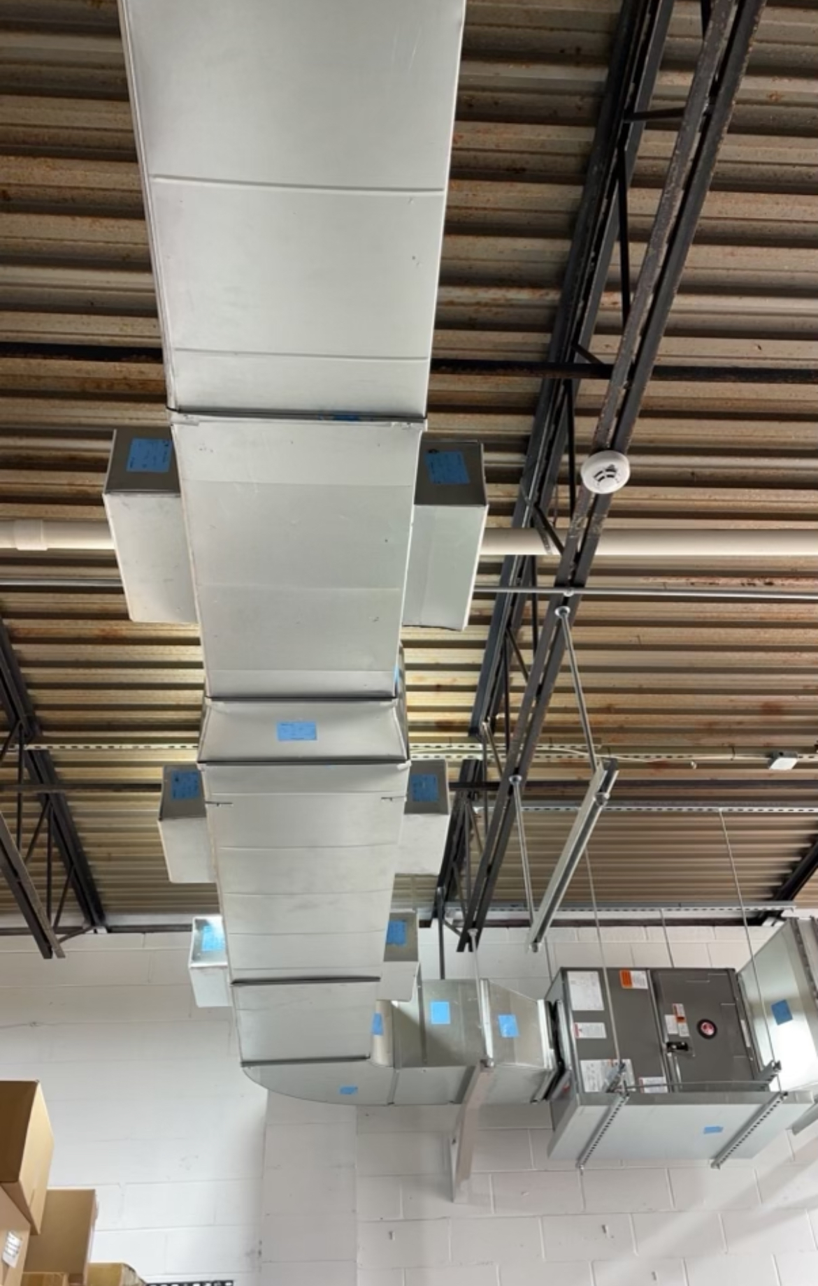 A row of white ducts hanging from the ceiling of a building.
