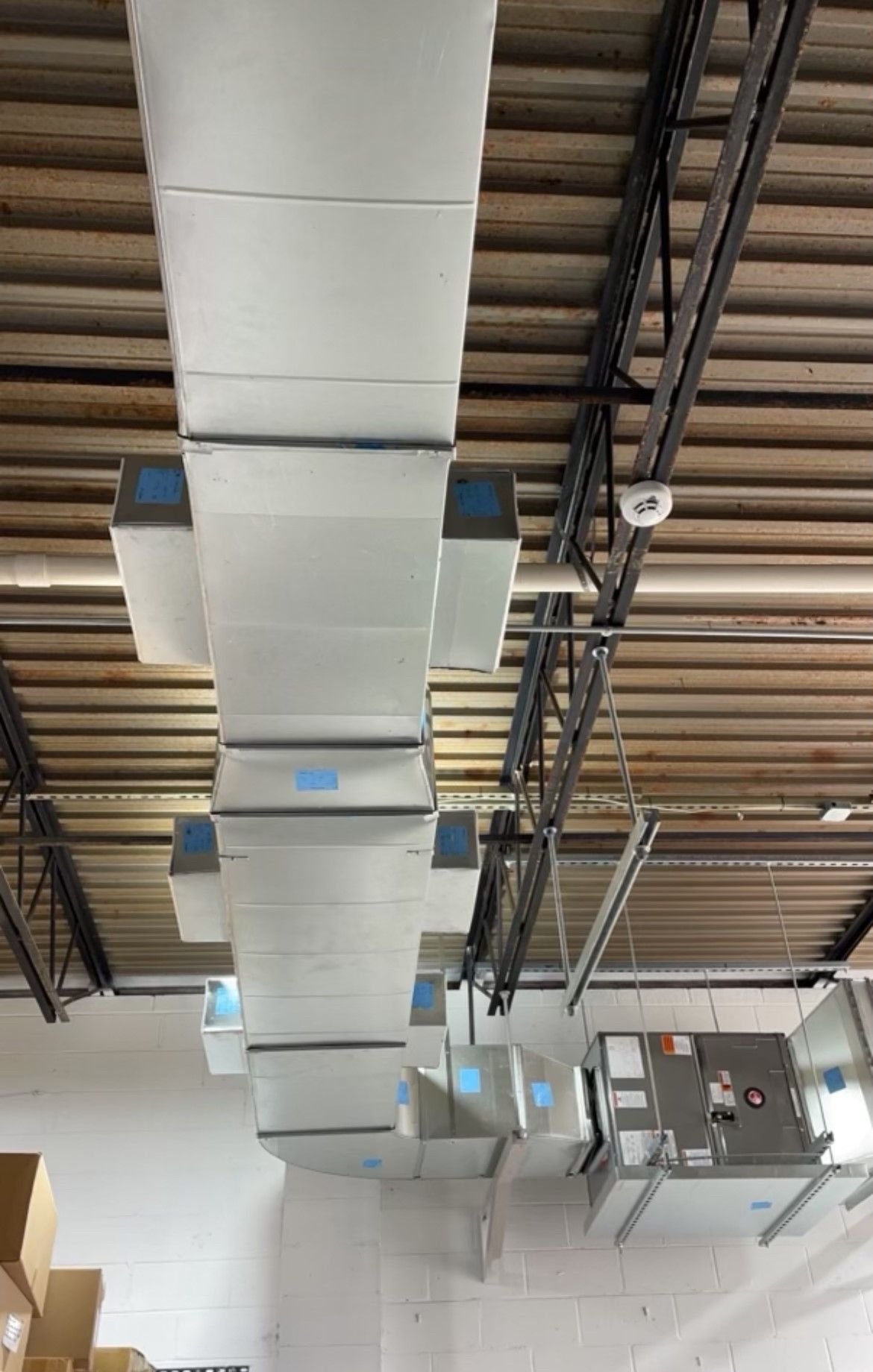 There are a lot of ducts hanging from the ceiling of a building.