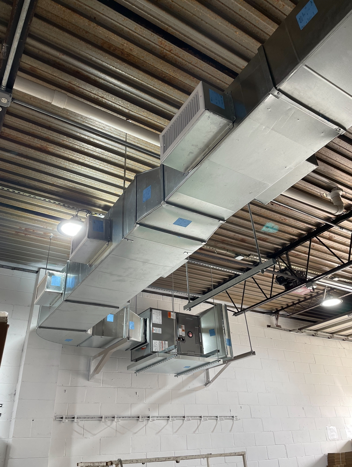 There are many ducts hanging from the ceiling of a building.