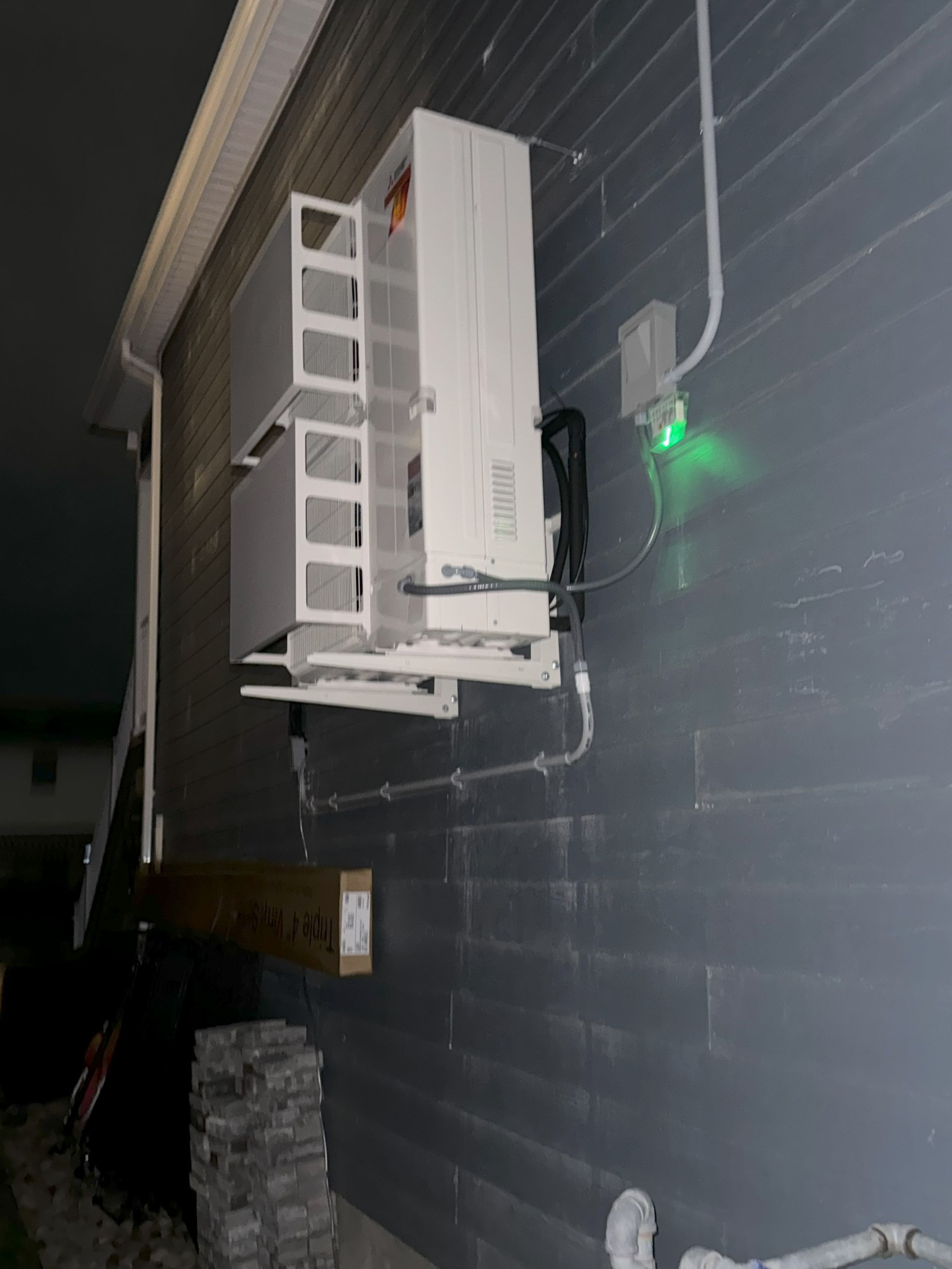 A white air conditioner is mounted on the side of a building.
