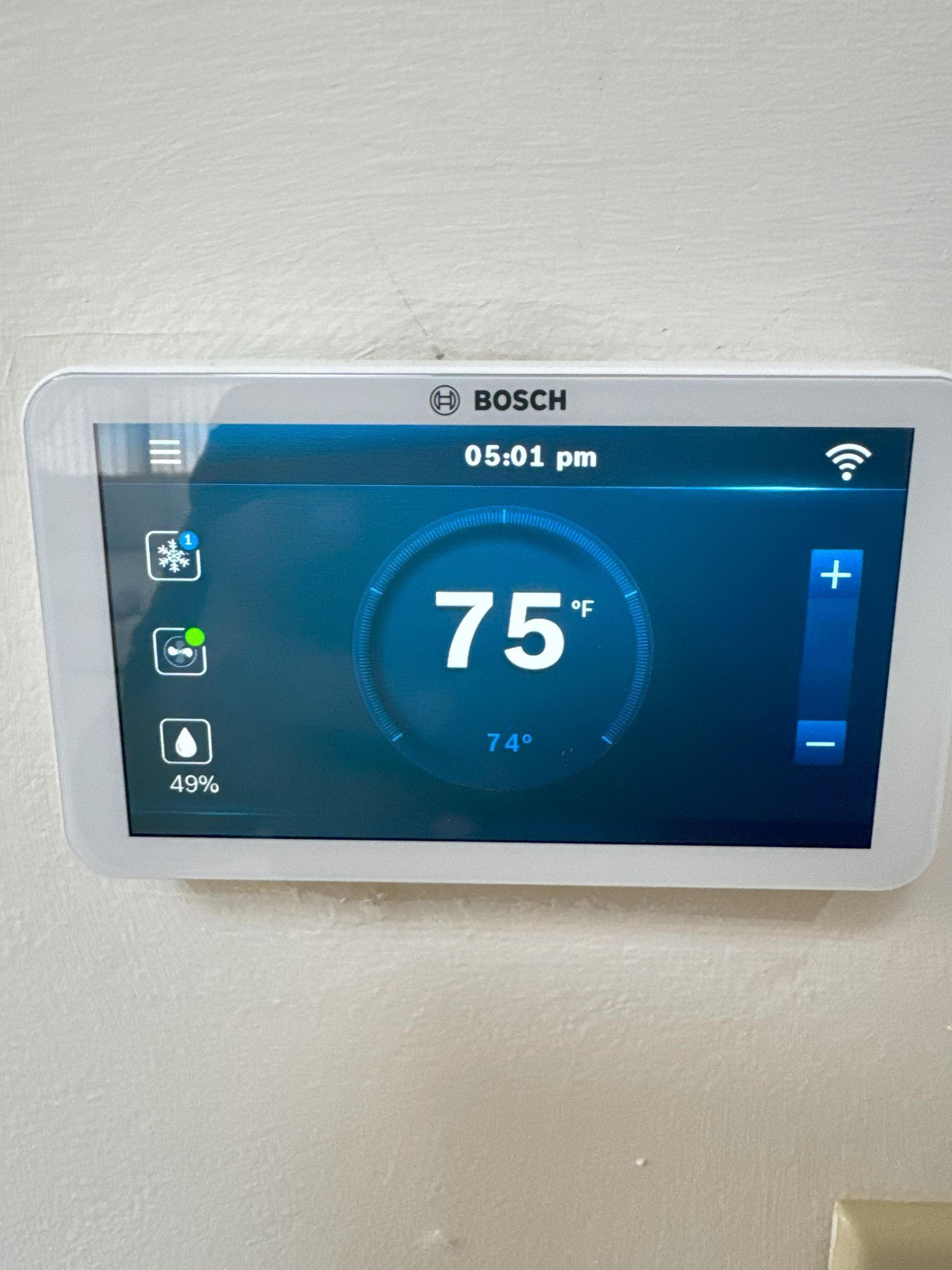 A bosch thermostat is hanging on a white wall.
