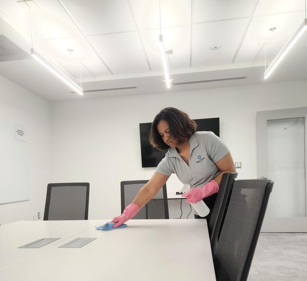 Person wearing a face mask and gloves cleaning a table in a waiting room.