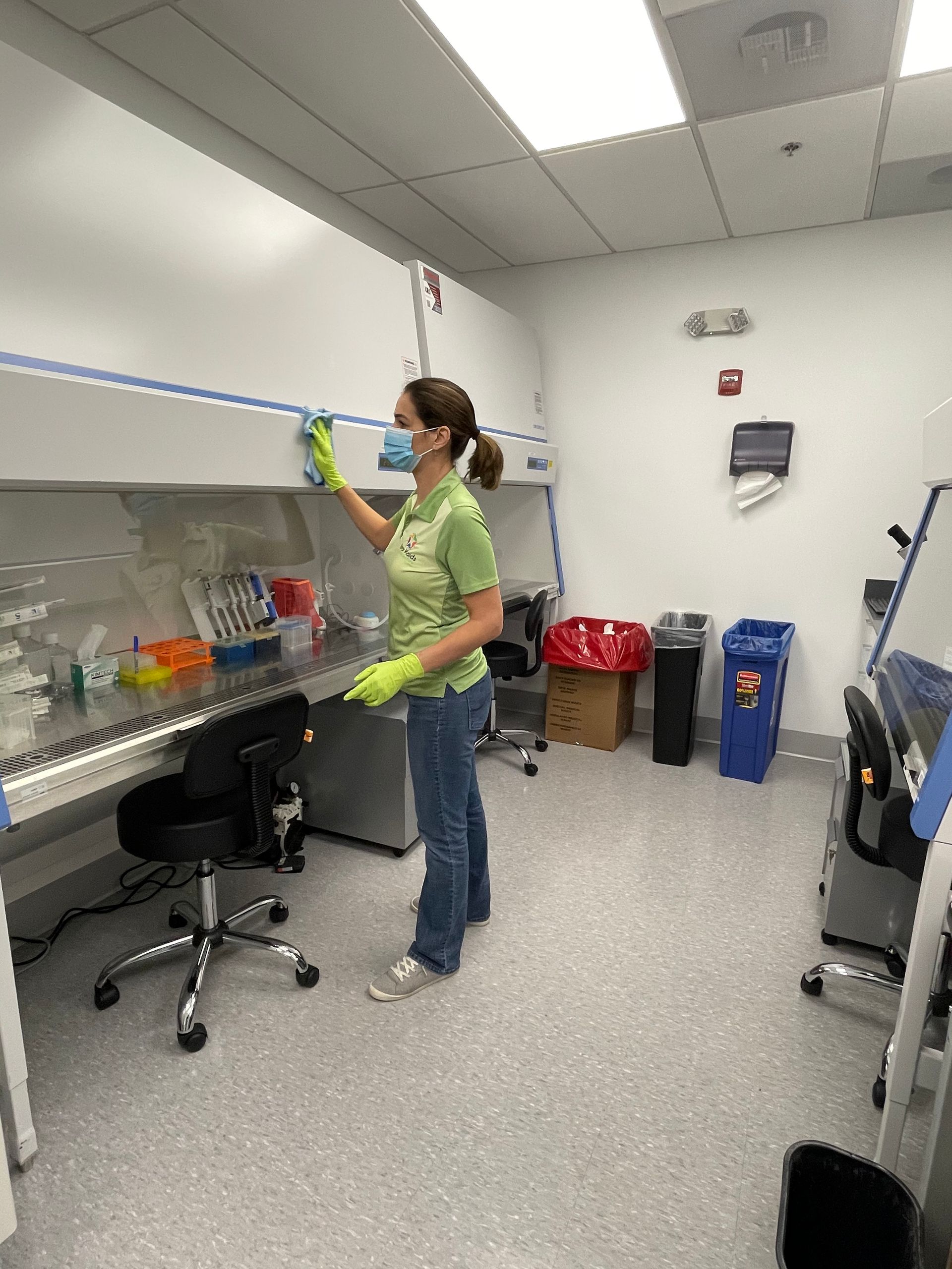 A person in lab attire cleaning a laminar flow hood in a laboratory.