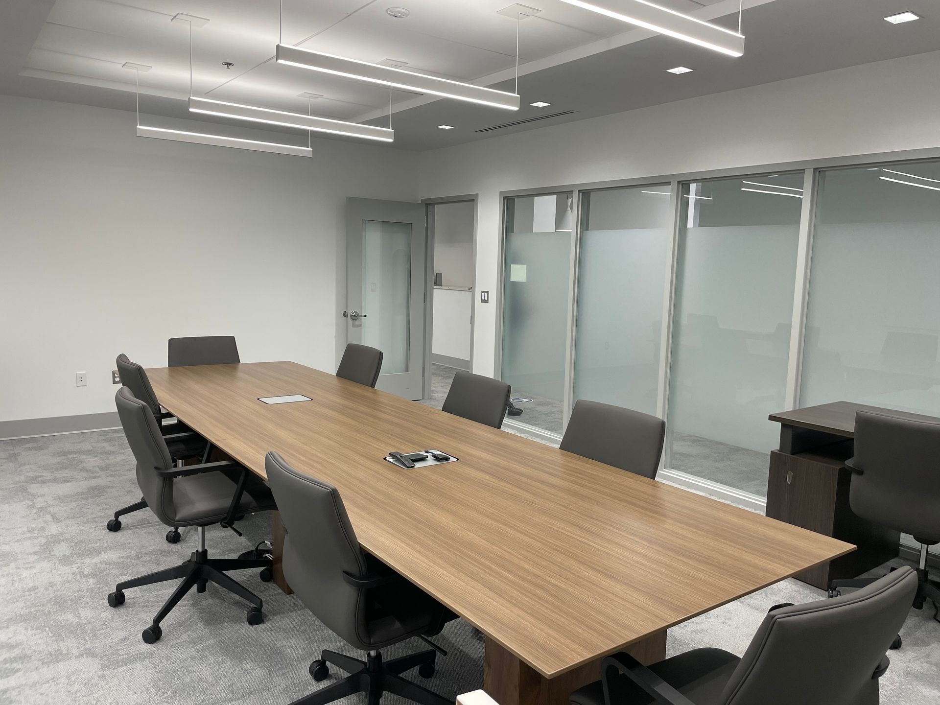 Conference room with long wooden table, chairs, and frosted glass windows.