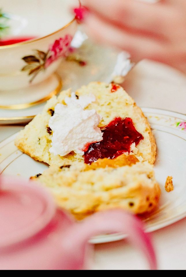 A close up of a scone with jam and whipped cream on a plate