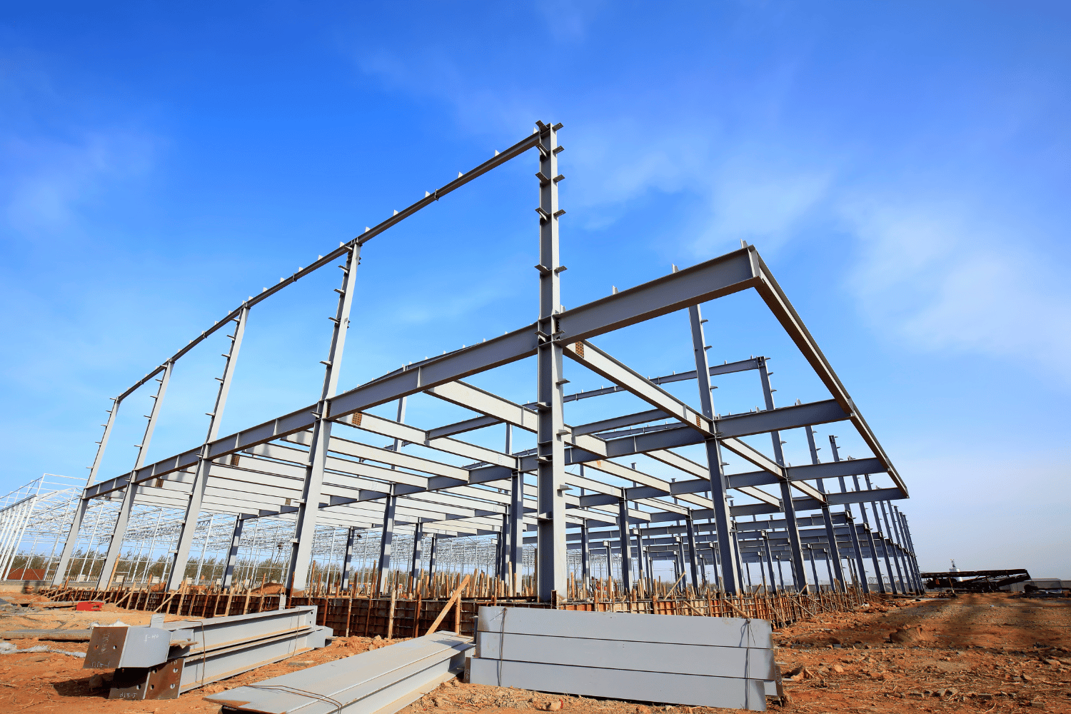 Steel frame of a building under construction against a clear blue sky.