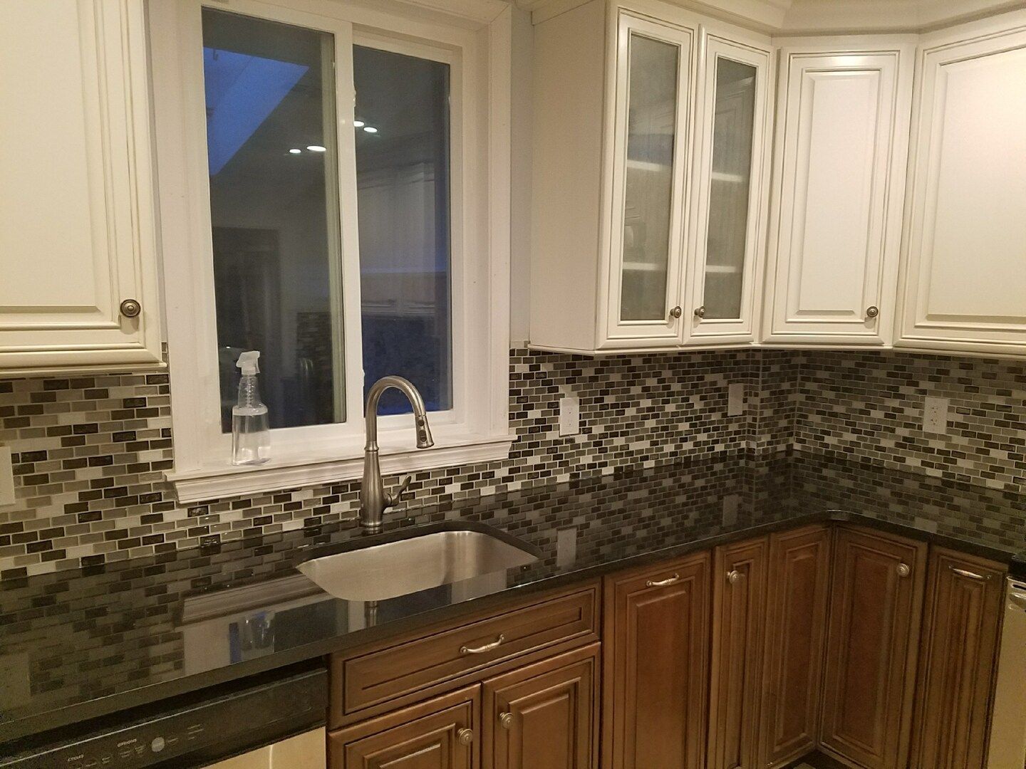 A kitchen with a sink , cabinets , and a window.