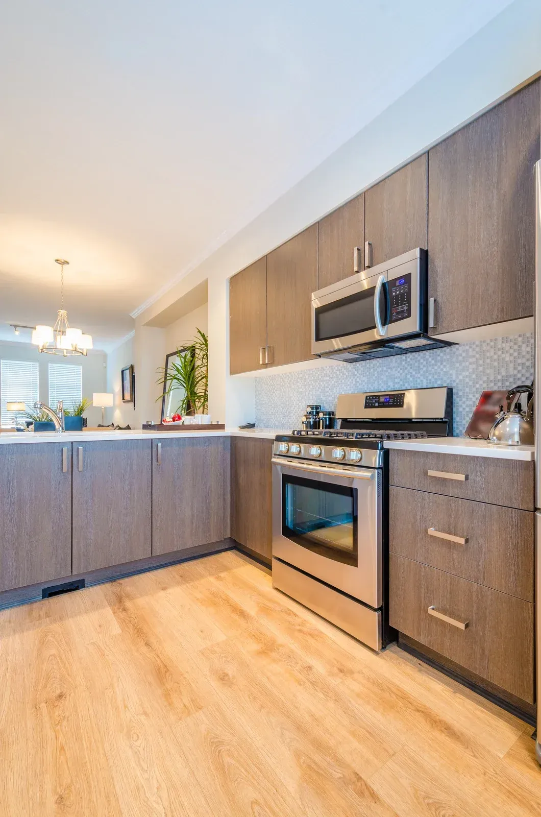 Modern kitchen with stainless steel appliances, gray cabinets, and light wood floors.
