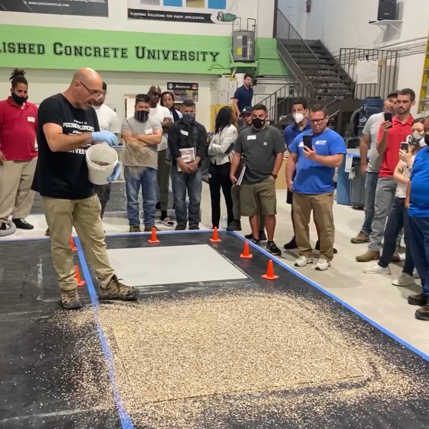 A group of people are gathered in front of a sign that says finished concrete university
