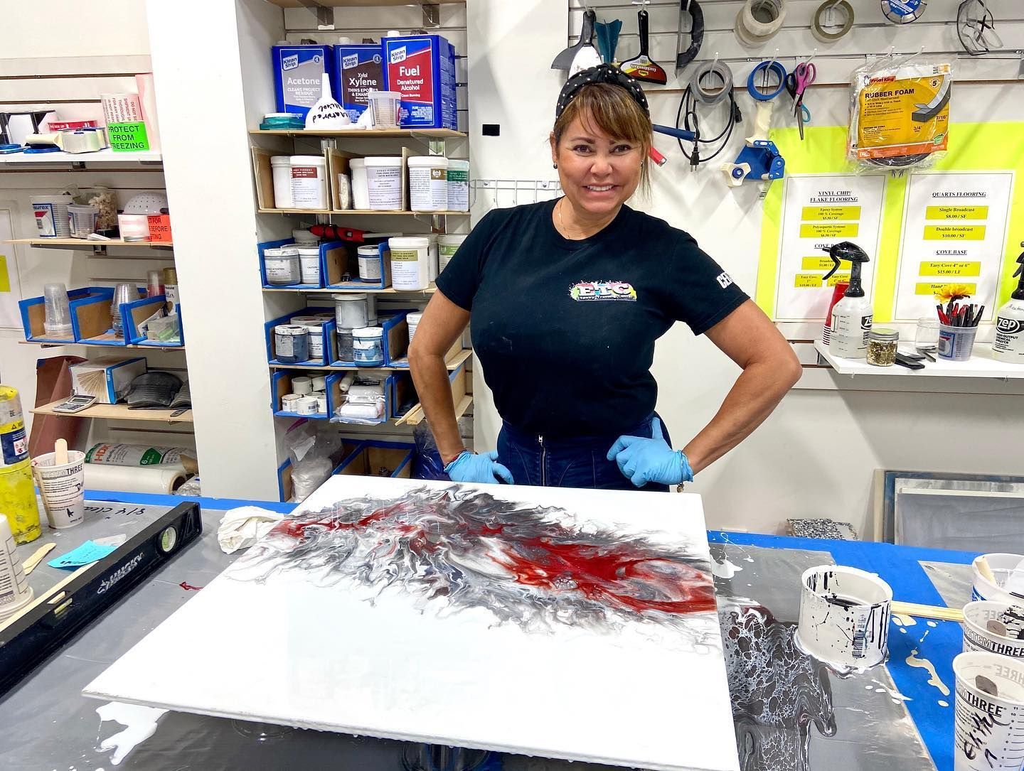 A woman is standing in front of a painting on a table.