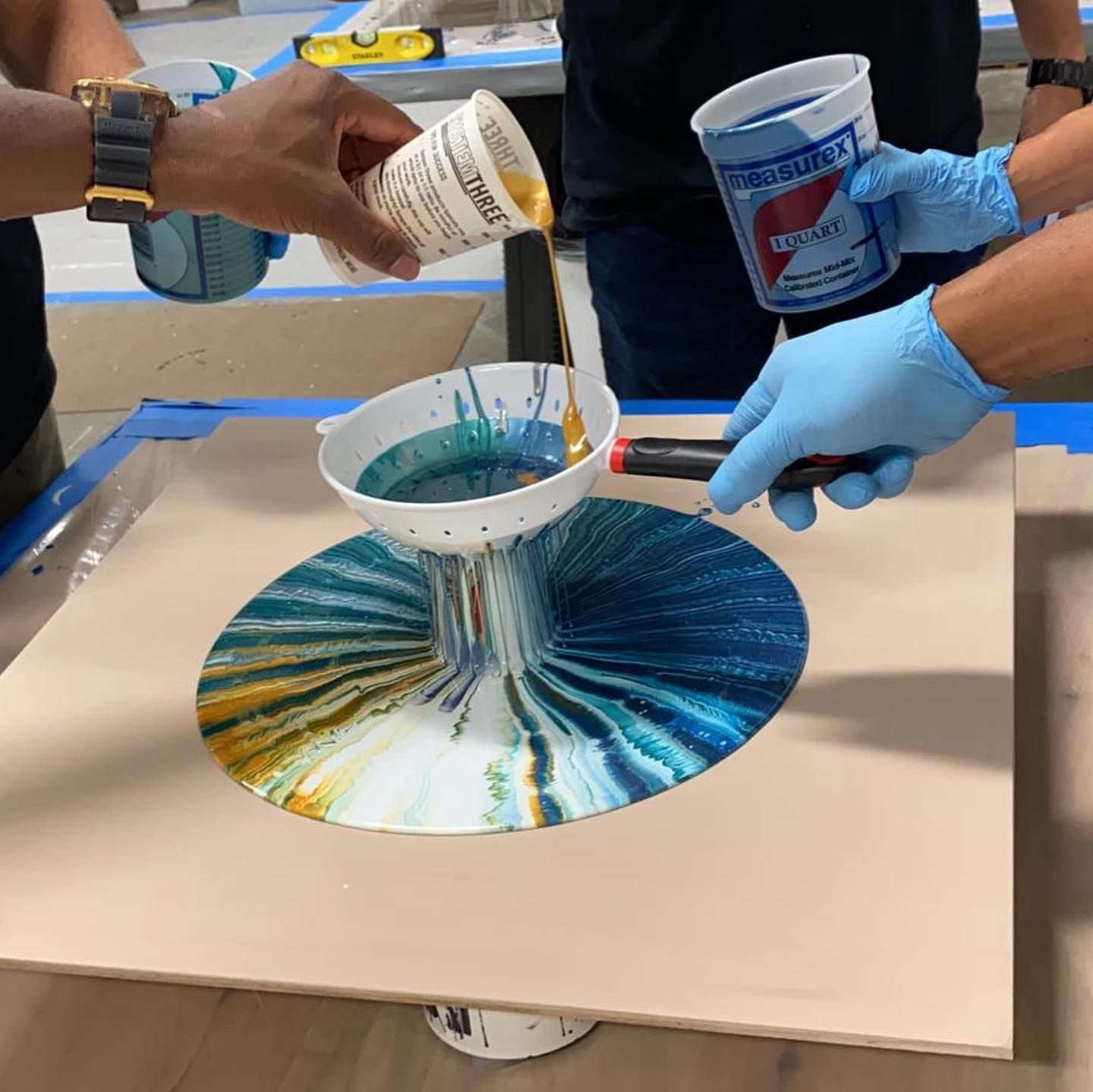 A pepsi cup is being poured into a bowl of paint