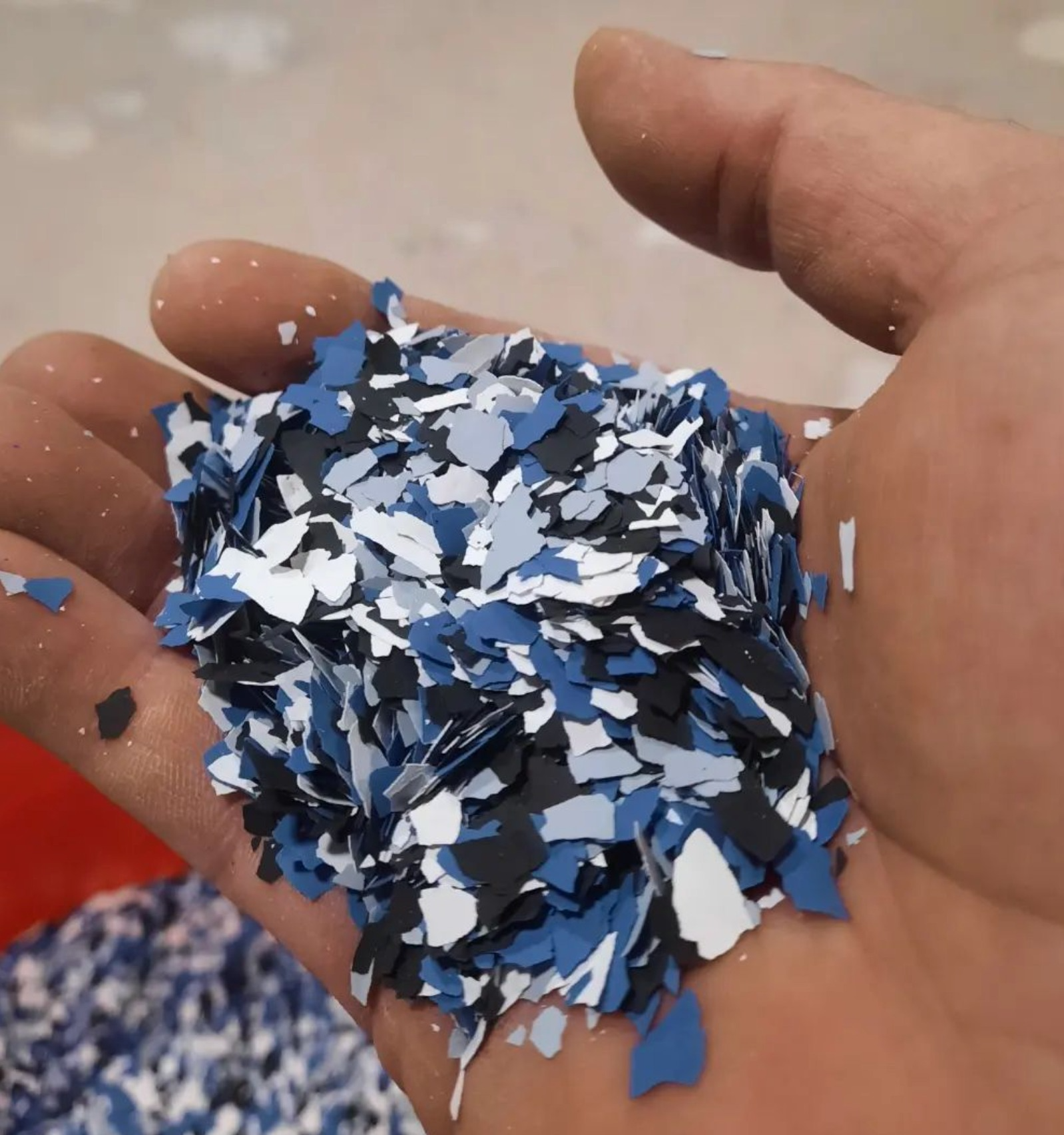 A hand is holding a pile of blue white and black flakes